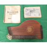 A wooden Zither musical instrument with white detailing to edges, spare strings and music sheets