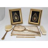 A brass brush set comprising of two brushes and a mirror with embroidered backs and an embroidered