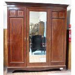 An Edwardian mahogany triple wardrobe with satinwood crossbanding, the shaped cornice above