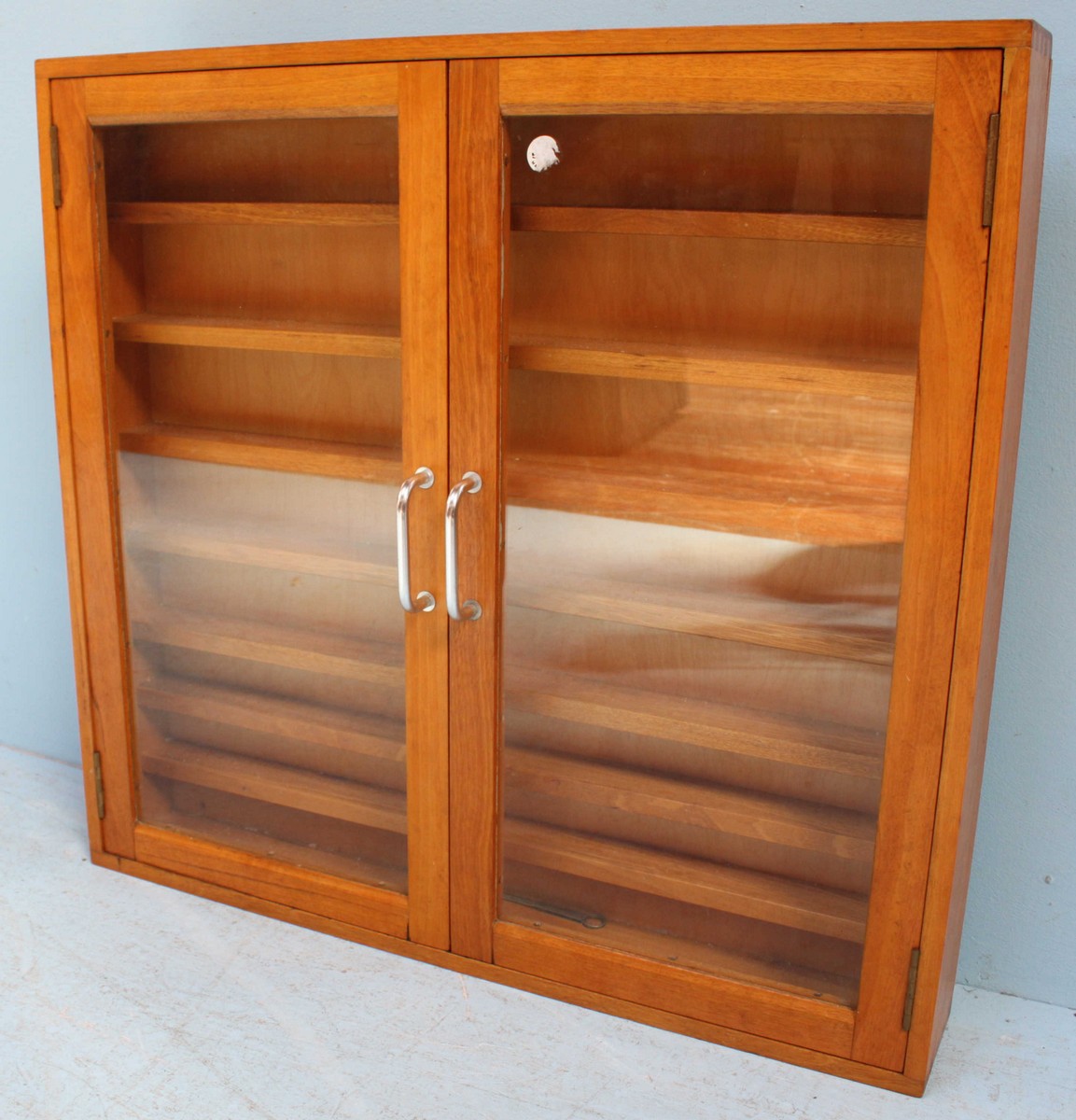 A stained wood two door hanging display cabinet, the two glazed doors enclosing seven shelves.