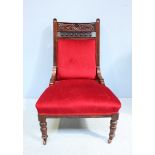 A Victorian mahogany nursing chair, with carved back, deep red fabric upholstery with frilled gimp