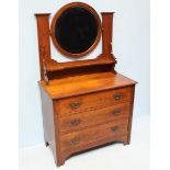 An Edwardian oak dressing table, the central, circular bevelled mirror above a shelf and supported