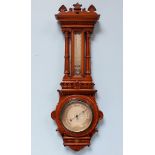 An Edwardian oak cased aneroid barometer, with shaped finial, dentil moulding and a centrally glazed