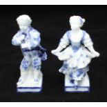 A pair of blue and white painted German porcelain figures (possibly Dresden) depicting a boy playing