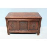 A 20th century oak coffer, the hinged top enclosing storage space, with three carved panels to the