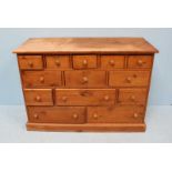 A waxed pine sideboard comprising of thirteen drawers of varying shapes and sized, with turned pulls