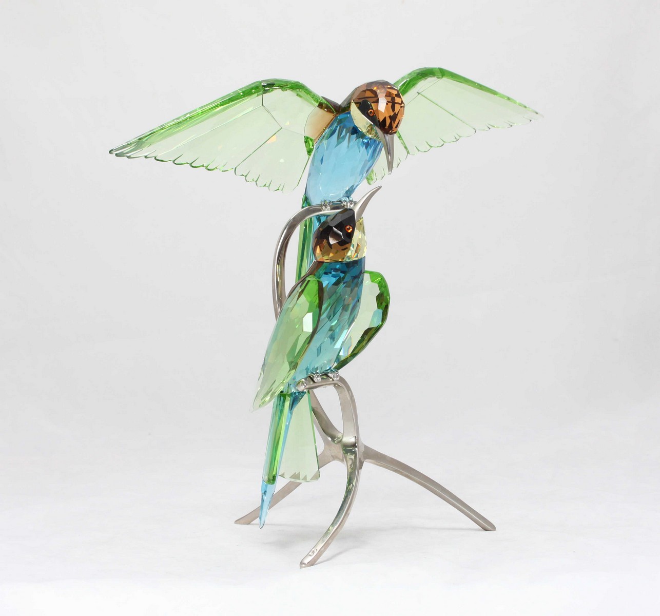A Swarovski crystal 'Bee Eaters peridot' figurine, depicting two birds sitting upon chrome metal