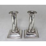 A pair of Edwardian loaded silver squat candlesticks, of plain Doric form with beaded sconce rims,