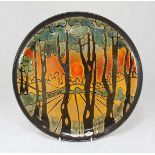 A Poole pottery Aegean pattern charger, depicting a sun set in a forest landscape, signed J.