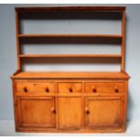 A large pine dresser, the back with shaped cornice and two shelves, leading to a plain top, with