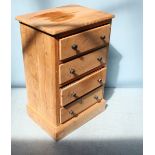 A stripped pine narrow chest of four drawers, with turned pulls and raised on pedestal base. 60cm