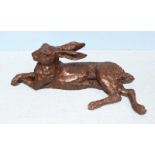 A life-size hollow cast and patinated bronze figure of a recumbent hare, 63cm x 23cm