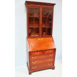 An early 20th century mahogany bureau bookcase, the shaped cornice with dentil moulding above two