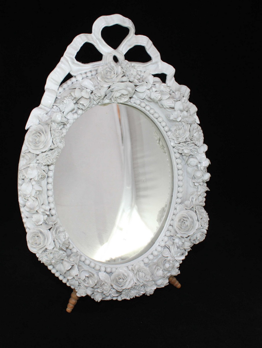 A Meissen Blanc-de-Chine porcelain oval easel mirror, modelled with tied-bow crest, bead and