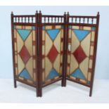 An Edwardian three-fold stained glass screen, with turned pegs to top above multi-coloured lead