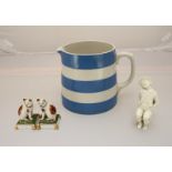 A white Worcester porcelain figure of a boy sat on a chair and a blue and white Cornish ware jug