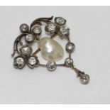 A silver set on gold brooch set with thirteen old cut diamonds and a baroque pearl drop to the