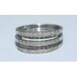 A 9ct white gold diamond ring, designed as five joined bands of alternating height, each channel set