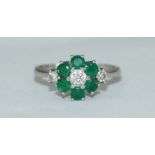 An 18ct white gold, diamond and emerald cluster ring, flower design, three diamonds estimated 0.