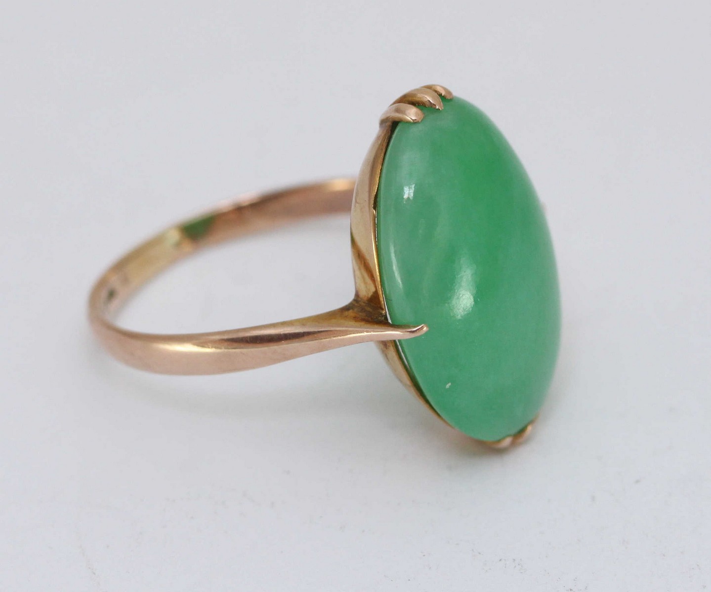 A 14K gold ring, claw-set with an oval cabochon polished jade, measuring 19x14mm, probably Honk