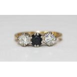 An 18ct gold three stone ring, centrally claw set with a sapphire and flanked by two round brilliant