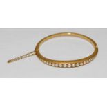 A 15 carat gold hinged bangle set with graduated half pearls, circa 1890.