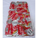 A solid aluminium rectangular wall plaque made from a quantity of machine crushed Coca-Cola cans,