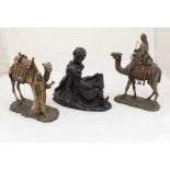 A resin figure-group depicting two children reading, together with two resin camels with figures.