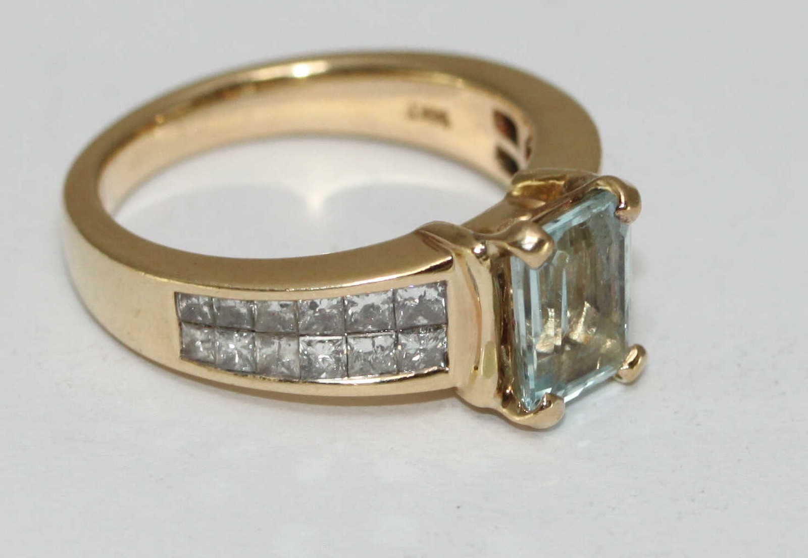 A 14 carat gold ring claw set with a central rectangular aquamarine and channel set with twenty four