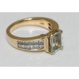 A 14 carat gold ring claw set with a central rectangular aquamarine and channel set with twenty four