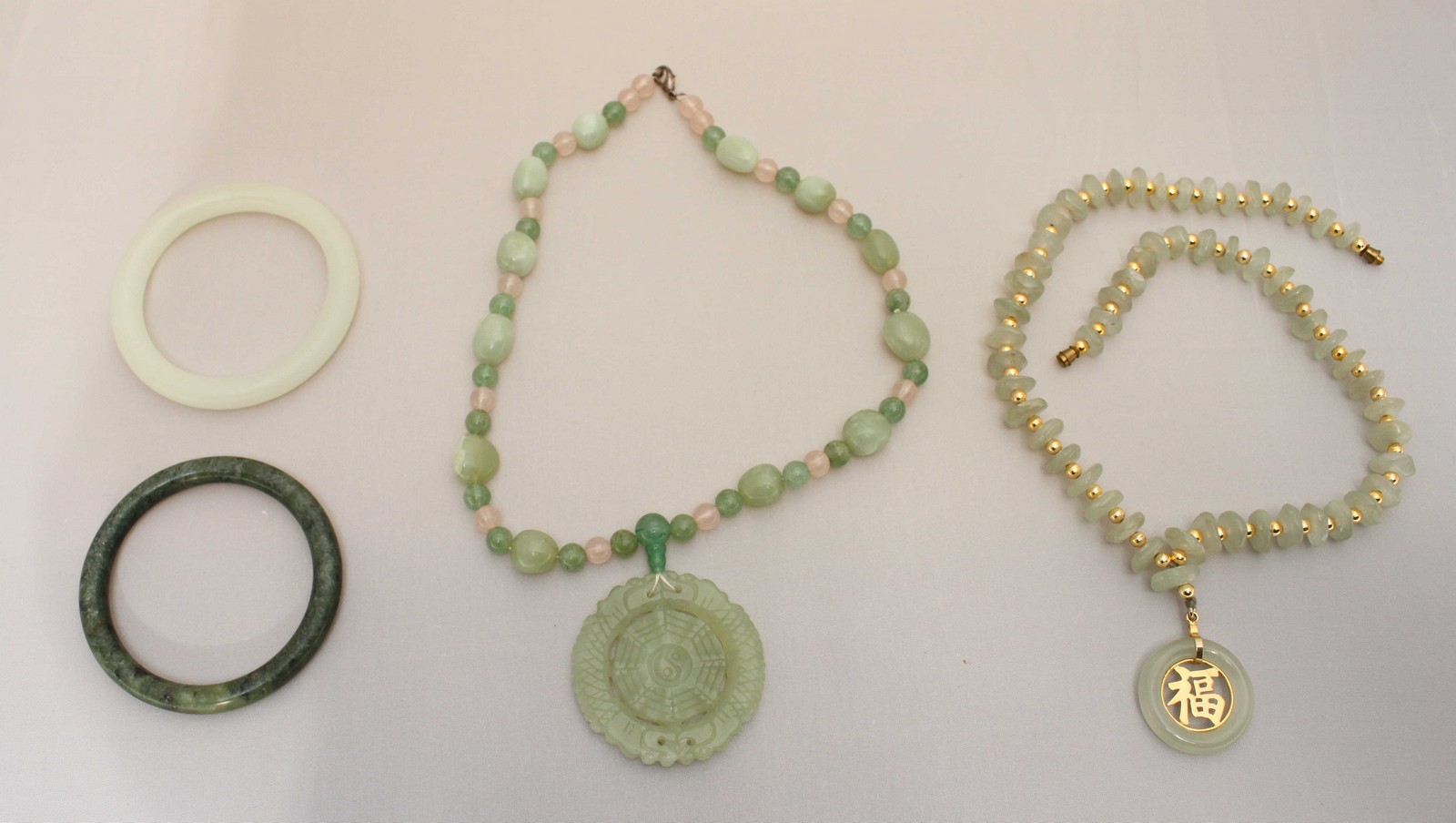 An assortment of jade coloured jewellery items including bangles, necklaces and pendants.