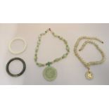 An assortment of jade coloured jewellery items including bangles, necklaces and pendants.