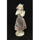 A Lladro porcelain figure of a young girl with a basket of flowers. (No. 1.417) 26cm high.