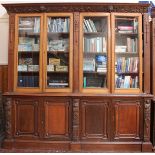 A large 19th century oak bookcase, the cornice decorated with classically carved cherubs, scrolls