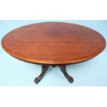 A Victorian stained walnut oval tilt-top table, raised on five turned columns to four carved and