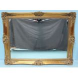 A rectangular bevelled mirror, in ornately carved gilt frame. 77 x 102cm including frame.