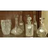 Six assorted cut glass decanters, five with ceramic spirit labels and a cut glass vase.