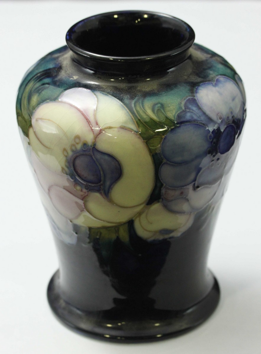 A Moorcroft pottery vase of cylindrical tapering form, with blue and white pansy decoration to a