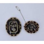 Two early Victorian yellow metal mourning brooches, each with scrollwork frame to a black enamel