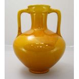 A Burmantoft Faience pottery two handled vase, model no. '1819' decorated in a yellow glaze. 26cm