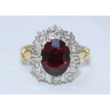 An 18ct yellow gold diamond and ruby ring, centrally set with a synthetic oval faceted ruby 10.04