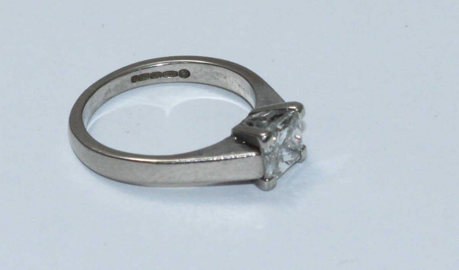 An 18ct white solitaire diamond gold ring, centrally four claw set with a princess cut diamond,