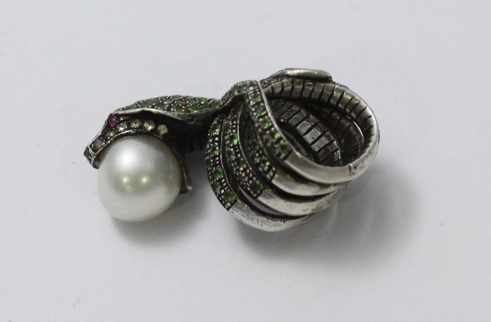 A white-metal ring modelled as a coiled snake, pave-set with green stones and holding a large - Image 5 of 5