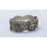 A white metal (tests as .800 grade silver) Chinese hinged filigree bangle, with floral decoration.