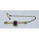 A yellow metal brooch with oval amethyst coloured stone, surrounded by small seed pearls, gross