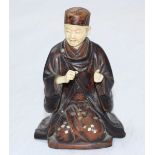 A Japanese Meiji Period Carved Ivory and stained boxwood Okimono figure of a kneeling monk, with