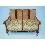 An early 20th century walnut bergere suite comprising of two armchairs and a two-seater sofa, with