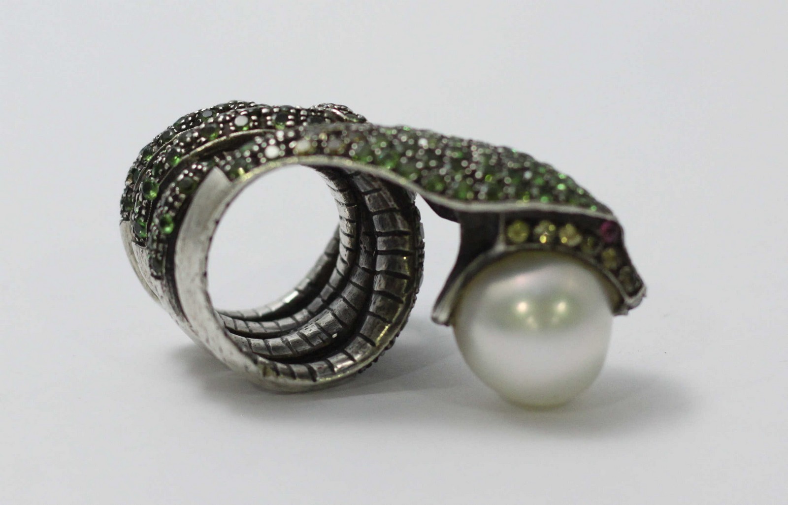 A white-metal ring modelled as a coiled snake, pave-set with green stones and holding a large - Image 2 of 5