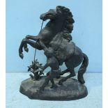 A cast metal figure of a rearing stallion and man dressed in loin cloth, approximately 40cm high
