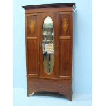 An Edwardian inlaid mahogany wardrobe, the single door with an oval mirror, above a single long